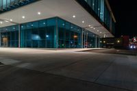 an empty building with a lot of glass on the outside of it at night with no one inside the glass