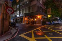 a street corner with yellow painted stripes, and a bicycle at night in the background