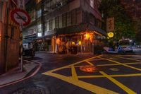 a street corner with yellow painted stripes, and a bicycle at night in the background