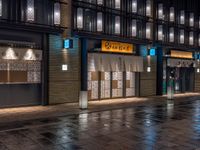 a large brick sidewalk with a store front at night time and a sign that says