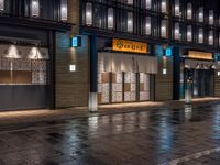 a large brick sidewalk with a store front at night time and a sign that says