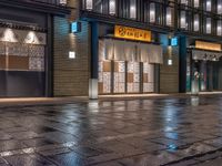 a large brick sidewalk with a store front at night time and a sign that says