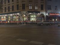 the street has light streaks from cars coming in the window of it and a building that is empty