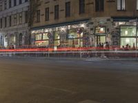 the street has light streaks from cars coming in the window of it and a building that is empty