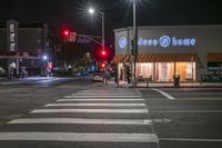 there is a crosswalk that has people walking across it at night outside a local business