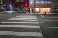 there is a crosswalk that has people walking across it at night outside a local business