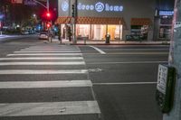 there is a crosswalk that has people walking across it at night outside a local business