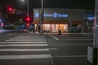 there is a crosswalk that has people walking across it at night outside a local business