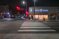 there is a crosswalk that has people walking across it at night outside a local business