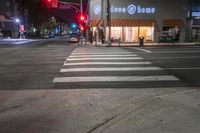 there is a crosswalk that has people walking across it at night outside a local business