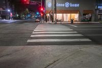 there is a crosswalk that has people walking across it at night outside a local business