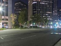 some city buildings and trees on an empty street at night with lights on them and people walking