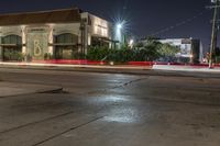 the city is in an empty lot at night, with traffic passing through the intersection