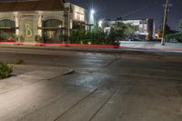 the city is in an empty lot at night, with traffic passing through the intersection