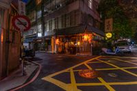 a street view at night with a traffic sign and motorcycle riding down the road in front of it