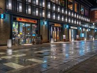 a large brick sidewalk with a store front at night time and a sign that says