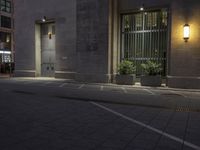 an empty street with windows and street lights on the sidewalk in front of a building