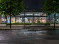 a building that has a lot of trees in front of it at night time,