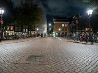 a brick street with many bikes parked near it at night time, all on the ground