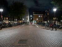 a brick street with many bikes parked near it at night time, all on the ground