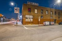 a group of parked cars near an old building at night, with a street sign and other graffiti on it