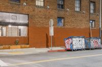 a group of parked cars near an old building at night, with a street sign and other graffiti on it