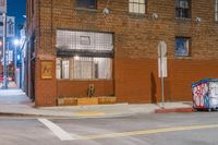 a group of parked cars near an old building at night, with a street sign and other graffiti on it