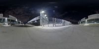 the view from a fish eye lens into a baseball stadium at night, with a person on a skateboard in the foreground