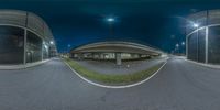 a fisheye lens photograph of some buildings and streetlights on a highway at night