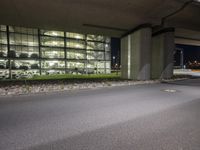 there is an empty parking lot outside a building by the street corner at night time