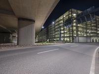 there is an empty parking lot outside a building by the street corner at night time