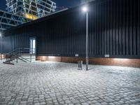 a city sidewalk with bricks in front of it at nighttime at night time with lights