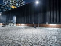 a city sidewalk with bricks in front of it at nighttime at night time with lights