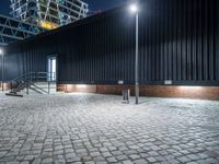 a city sidewalk with bricks in front of it at nighttime at night time with lights