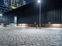 a city sidewalk with bricks in front of it at nighttime at night time with lights