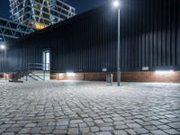 a city sidewalk with bricks in front of it at nighttime at night time with lights