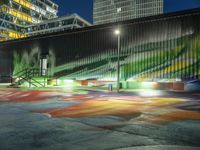 a large green building with stairs leading up to a walkway with painted street lights on it