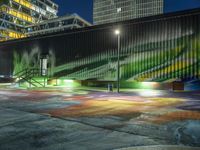 a large green building with stairs leading up to a walkway with painted street lights on it