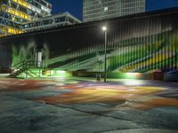 a large green building with stairs leading up to a walkway with painted street lights on it