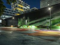 a large green building with stairs leading up to a walkway with painted street lights on it