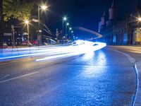 street with lights moving fast through it at night time and in the background a building