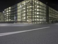 night scene, with some glass building next to it on a street corner with traffic signs and no parking sign