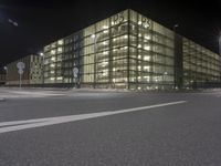 night scene, with some glass building next to it on a street corner with traffic signs and no parking sign