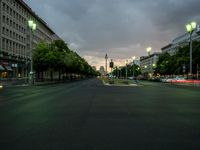 a street lined with tall buildings in the evening time with green streetlights on them