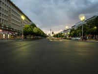 a street lined with tall buildings in the evening time with green streetlights on them