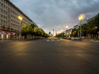 a street lined with tall buildings in the evening time with green streetlights on them