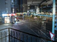 an intersection with buses, lights and shops at night time on the road side of a city street