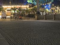 a person is standing on an empty brick walkway by the tv tower and trees with lights