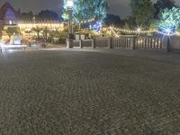 a person is standing on an empty brick walkway by the tv tower and trees with lights