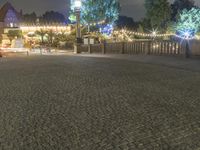 a person is standing on an empty brick walkway by the tv tower and trees with lights